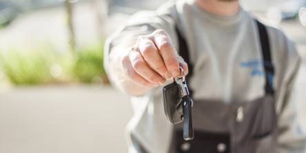 Man holding out a set of car keys.