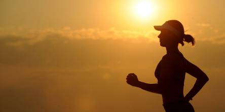 Woman jogging with the sunset in the background.