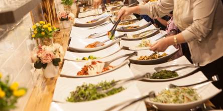Buffet table with salads, vegetables, and main dishes served at a corporate event, showcasing professional catering setup.