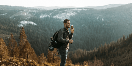 man wearing black jacket standing on mountain