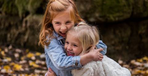 Two little girls outside hugging.