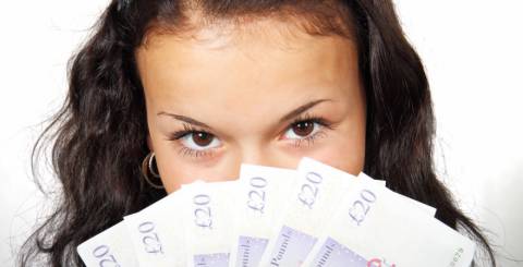 Woman looking at the camera with a fan of £20 notes.