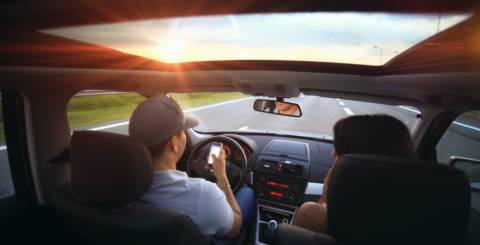 Man and woman sitting in the front seat of a car whilst driving.