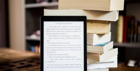 ebook reader in front of a pile of books